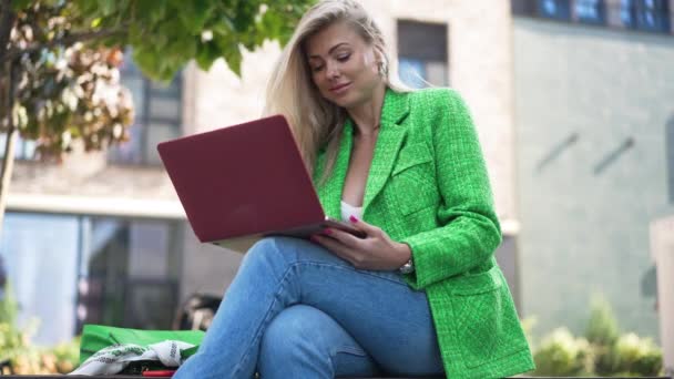 積極的な集中ブロンドの女性のオンライン都市の通りにラップトップで座ってメッセージング 自信を持っている白人女性の肖像画日の出市の屋外で焦点を当てた スローモーション — ストック動画