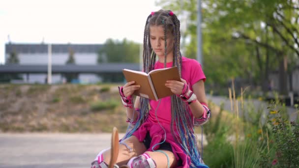 Özümsenmiş Genç Kız Sesli Kitap Okuyor Kaykayla Şehir Bankında Oturuyor — Stok video