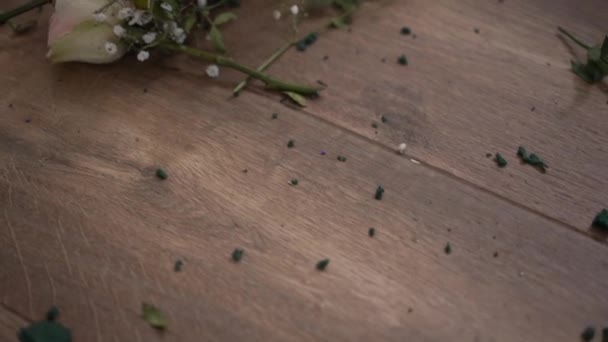 现场摄象机缓慢地沿着散落在木地板上的花朵移动 特写高角镜破碎花束 室内无人 分手和离婚的概念 — 图库视频影像