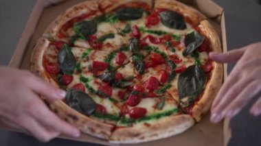 Kadın eli kesilen ve yavaş çekimde ayrılan yakın plan lezzetli pizzalar. Tanımlanamayan genç beyaz kadınlar içeride lezzetli abur cuburlar yiyorlar. Yüksek açılı yakından çekim.