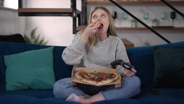 Ung Kvinna Äter Pizza Spel Online Sitter Soffan Vardagsrummet Frontvy — Stockvideo