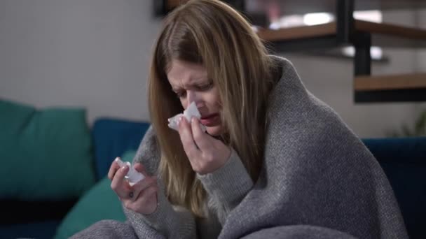 悲しい疲労病気の女性は鼻を吹き飛ばして鼻スプレーを遅い動きで吹きます 室内の自宅で座っている治療を適用する鼻水の病気の白人女性の肖像画 — ストック動画