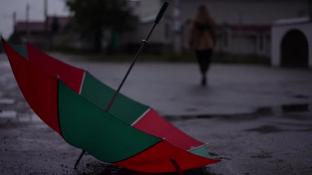 Close Red Green Umbrella Lying Road Blurred Young Woman Walking — Stock Video