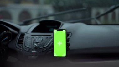 Araba panelinde yeşil ekran akıllı telefon. Araba silecekleri yavaş çekimde camları siliyor. Yağmurlu bir günde otomobilde hiç insan olmayan Chromakey telefon. GPS ve navigasyon kavramı