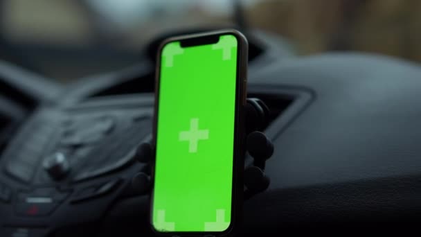 クローズアップ クロメイク スマートフォンアプリ ぼやけた車のワイパーは バックグラウンドでフロントガラスをワイプ スローモーションで拭きます 雨の日に自動車の緑色のスクリーンのタッチスクリーンが付いているクローズアップ装置 — ストック動画