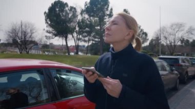 Beyaz kadının akıllı telefonda GPS uygulaması kullandığından emin değilim. Şehir sokağına bakıyorum. Açık hava telefon uygulamasında online haritayla yön arayan şüpheli sarışın kadının portresi.