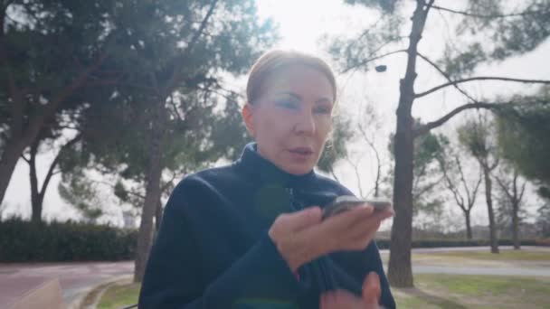 Szőke Beszél Kihangosítónál Napsugárban Parkban Koncentrált Súlyos Fehér Hölgy Portréja — Stock videók