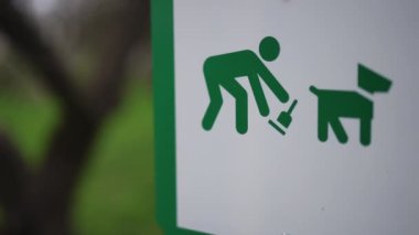 Köpeğinizin arkasını temizlemek için parka yakın çekim tabelası. Tabağında evcil hayvan resmi olan yeşil adam.