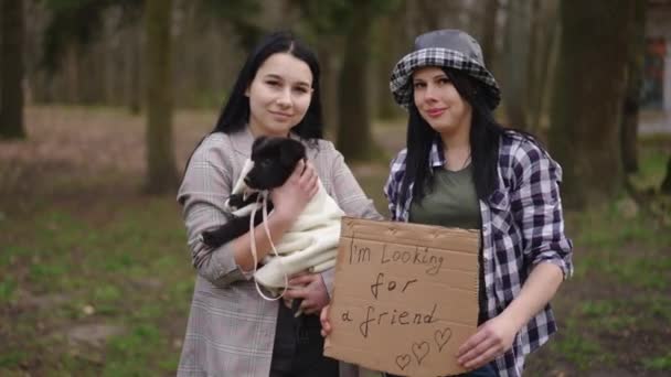 Due Giovani Donne Caucasiche Posa Con Cucciolo Sto Cercando Cartello — Video Stock