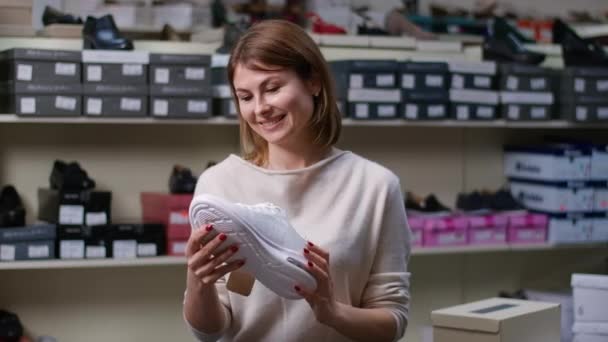 自信的年轻白种人女购物者检查白色运动鞋价签的画像 满意的女人选择黑色星期五的新运动服销售 — 图库视频影像
