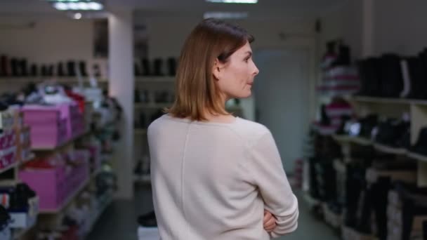 回头看 细心的白人女人环顾四周 看着站在室内商店货架上的鞋子 商场里年轻女性顾客选择新鞋子的想法 — 图库视频影像