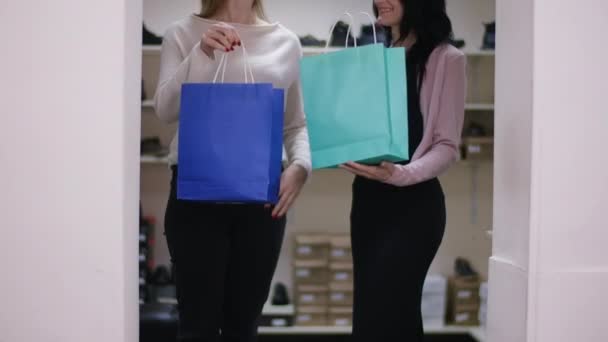 知られざる白人女性2人 ショッピングバッグを持った女性が屋内で外出 ブラックフライデーの販売で満足のいく女性クライアント — ストック動画