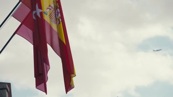 西班牙国旗的特写 飞机经过背景离开 户外阴天的早晨 侧视图挂在旗杆上的国家标志 — 图库视频影像