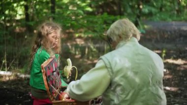Muzlu tatlı bir genç kız piknikte hasır sepette yemek arayan yaşlı bir kadınla konuşuyor. Büyüleyici beyaz bir torunun portresi fırıl fırıl fırıl dönüyordu.
