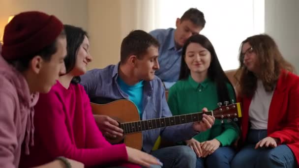 Grup Prieteni Relaxați Care Ascultă Bărbatul Cântând Chitară Stând Sufragerie — Videoclip de stoc