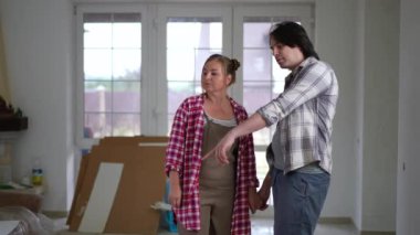 Büyük boy beyaz bir erkek ve kadın yeni bir evde durup ağır çekimde gülümseyip konuşuyorlar. Canlı kamera mutlu çifte yakınlaş. DIY kavramı