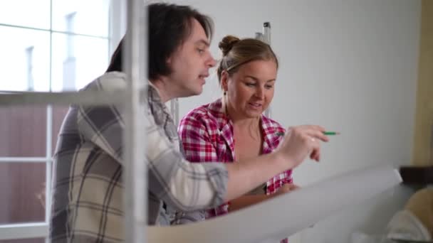 Concentrated Caucasian Husband Wife Discussing New House Renovation Drawing Blueprint — Stock Video