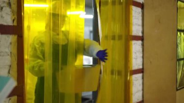 Üniformalı bir kadın geri dönüşüm istasyonunda sıralanmış çöp kutusuyla gülümsüyor. İçerideki çöpleri ayıran kendinden emin beyaz kadın işçinin portresi.