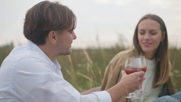 ガラスで赤ワインの匂いがするぼやけた女性と乾杯するサイドビューの笑顔 ハッピー ハンサム コーカサス ピクニック フィールド — ストック動画