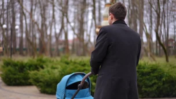 Śledzenie Ujęcia Szczęśliwego Ojca Spacerującego Wózkiem Dziecięcym Jesiennym Parku Rozglądającego — Wideo stockowe