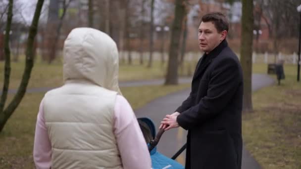 侧视图困扰着男人与生气的女人在公园小巷站在婴儿车旁边争论 不满的白人妻子在户外与不满意的丈夫争吵 — 图库视频影像