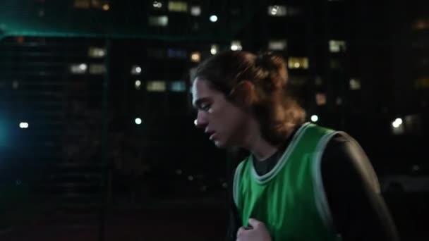侧视年轻人跳起来 瞄准户外篮球训练 集中注意力的白人运动员在夜市的黑暗中玩游戏 — 图库视频影像
