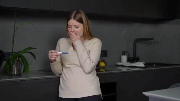震惊的白种人年轻女人捂着嘴看着阳性的怀孕测试 — 图库视频影像