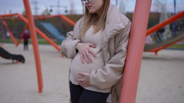 Αγνώριστη Μελαγχολική Έγκυος Γυναίκα Ακουμπισμένη Στύλο Στέκεται Στην Παιδική Χαρά — Αρχείο Βίντεο