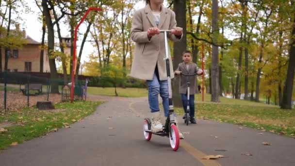 Tanımlanamayan Mutlu Kız Arka Planda Bulanık Bir Çocukla Scooter Kullanıyor — Stok video