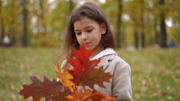 遠くから見える秋の花束を持つ思慮深いかわいい女の子の肖像画 ハッピーリラックスした白人子供の日 週末に公園で夢見る — ストック動画