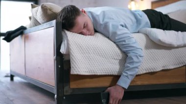 Canlı kamera, elinde akıllı telefonuyla yatakta uyuyan yorgun genç adama odaklan. Yorgun beyaz girişimci evdeki yatak odasında kestiriyor.