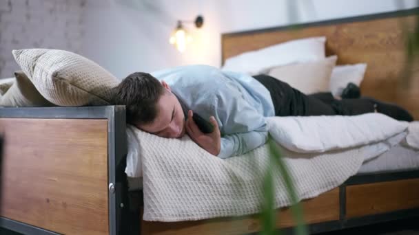 Joven Agotado Traje Durmiendo Cama Sosteniendo Teléfono Mano Caucásico Cansado — Vídeo de stock