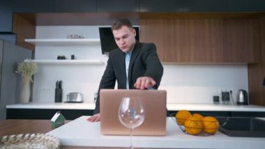 Takım elbiseli düşünceli bir adam dizüstü bilgisayarını kapatıp evde mutfakta durduğunu düşünüyor. Dahili ofiste başarılı beyaz iş adamının ön plan portresi.
