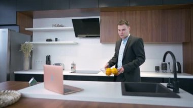 Genç iş adamı yavaş çekimde internette sörf yapan meyveli kaseyi masanın üstüne koyuyor. Sabahları mutfakta takım elbiseli, ciddi bir beyaz adamın portresi.