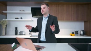 Ciddi konsantre olmuş bir adam dizüstü bilgisayarla mutfakta durup dilek diliyor. Kafkasyalı bağımsız girişimcinin yavaş çekimde başarıya ulaşmayı ummasının portresi