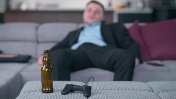 Prázdná Láhev Piva Joystick Rozmazaným Mladým Opilým Mužem Ležícím Pohovce — Stock video