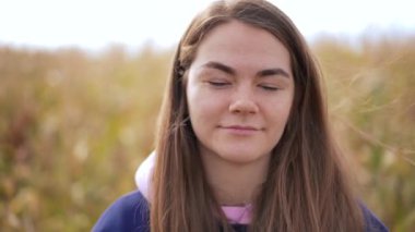 Sonbahar sahasında kameraya bakan kendine güvenen, gülümseyen güzel bir kadın. Açık havada poz veren beyaz bir kadının yakın plan portresi.