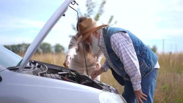 Widok Boku Skoncentrowany Starszy Mężczyzna Badający Zepsuty Samochód Jako Kobietę — Wideo stockowe