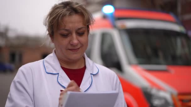 Uma Paramédica Sexo Feminino Está Contra Pano Fundo Uma Ambulância — Vídeo de Stock