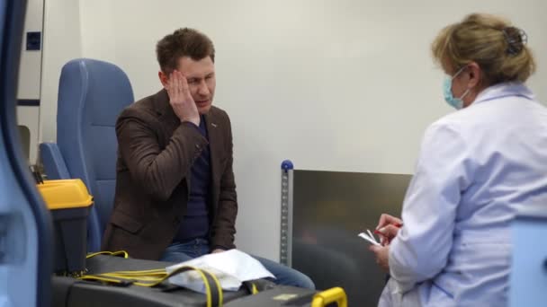 Manlig Patient Ambulans Och Klagar Till Kvinnlig Sjukvårdare Med Huvudvärk — Stockvideo