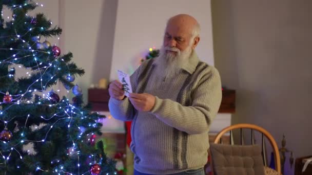 Anciano Canoso Casa Leyendo Una Tarjeta Mirando Árbol Navidad — Vídeo de stock