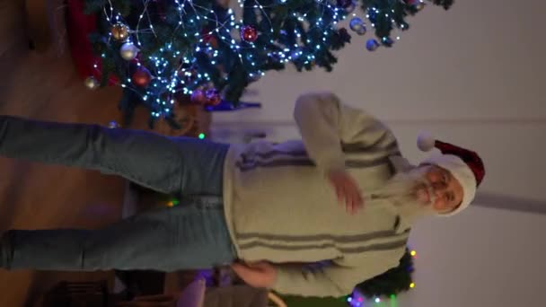 Κάθετη Βίντεο Ένας Ηλικιωμένος Άνδρας Τζιν Πουλόβερ Και Χριστουγεννιάτικο Καπέλο — Αρχείο Βίντεο