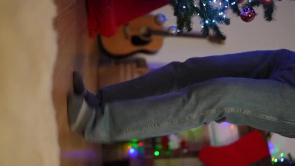 垂直ビデオ クリスマスツリーの近くで踊る男の足のクローズアップ — ストック動画