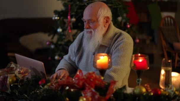 Sitter Vid Ett Festligt Bord Nära Julgran Med Laptop Äldre — Stockvideo