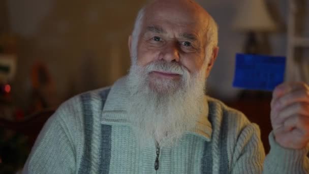Крупный План Пожилого Бородатого Мужчины Свитере Синей Карточкой Руке Усмешкой — стоковое видео