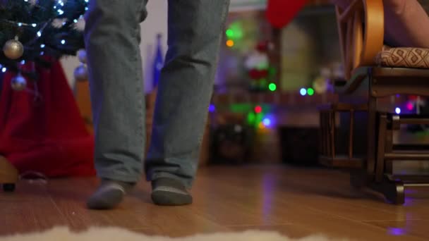クリスマスツリーの近くのパーケットフロアのジーンズと靴下のダンスの足のクローズアップ — ストック動画