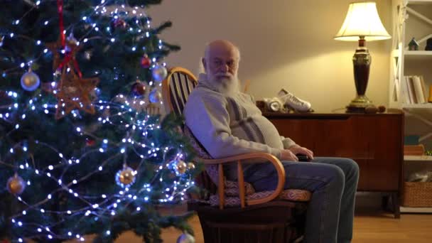Sentado Una Mecedora Anciano Barbudo Examina Atentamente Árbol Navidad Pie — Vídeo de stock