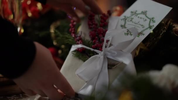 女性とクリスマスプレゼント 装飾されたお祝いのテーブルから絶妙なクリスマスプレゼントを取る女性の手 — ストック動画