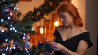 Noel ağacında elinde hediyeyle kızıl saçlı genç bir kadının Noel rüyası.