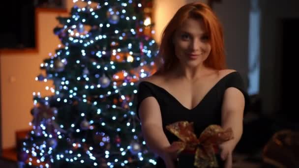 칵테일 드레스를 아름다운 여자가 카메라를 바라보고 정교하게 감싸는 크리스마스 선물을 — 비디오